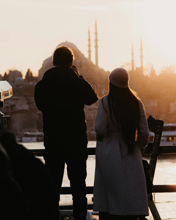 a man and woman on a dock watching the sun rise