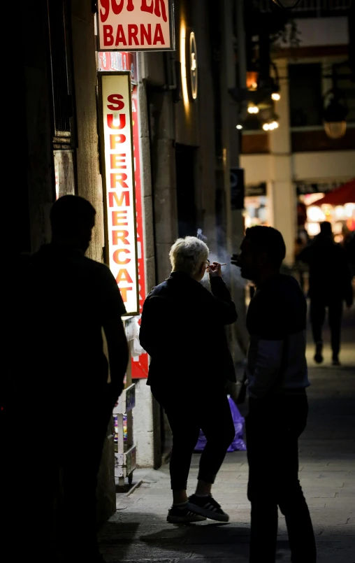 people are walking on the street and smoking in the dark