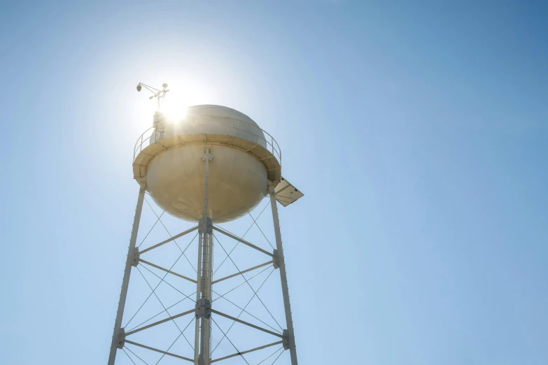 the sun is shining over the top of a white water tower