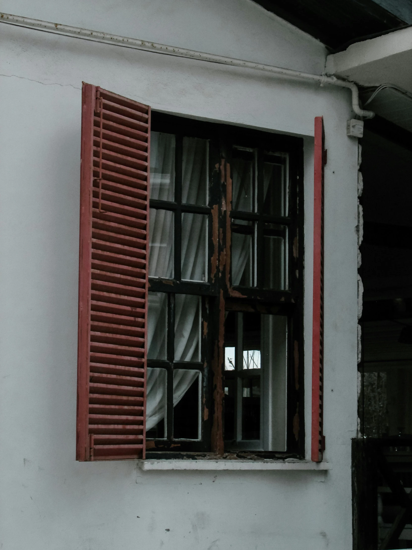 an old window with red wooden shutters in a white wall