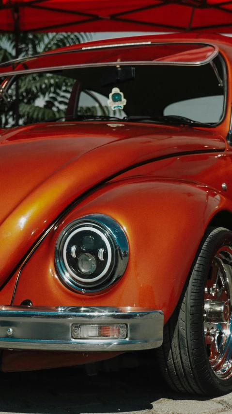 a car with a red body parked under a tent