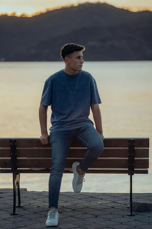 man in gray shirt sitting on bench near water