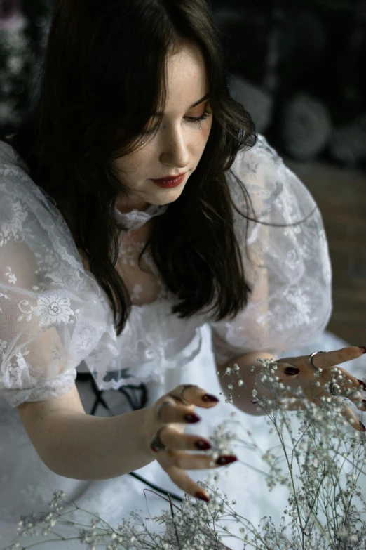 a woman in white dress holding flowers by scissors