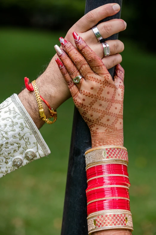 two hands each wearing different colored jewelry and celets