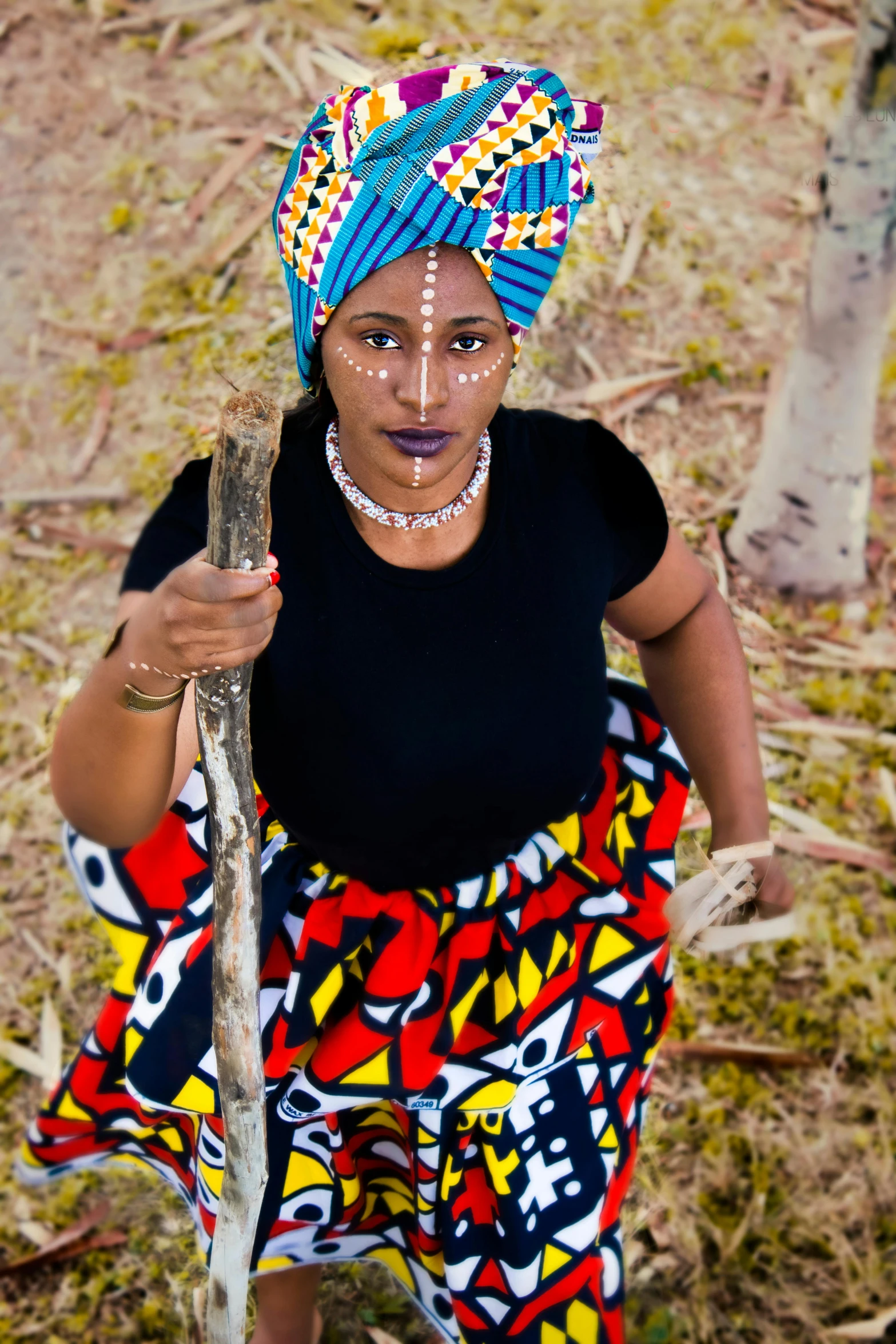 a woman with a beaded headdress holding a stick