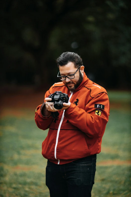a man in glasses holding a camera while standing outside