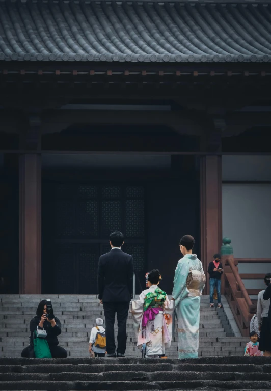 two people dressed in japanese attire standing near stairs