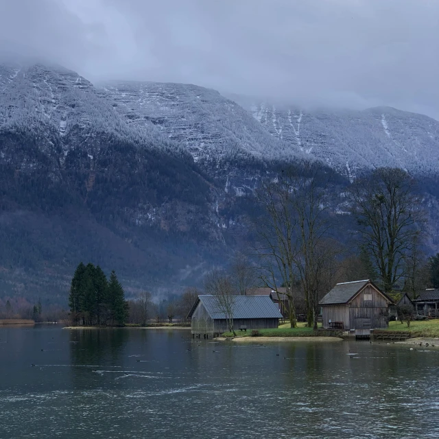 a body of water near a forest with mountains