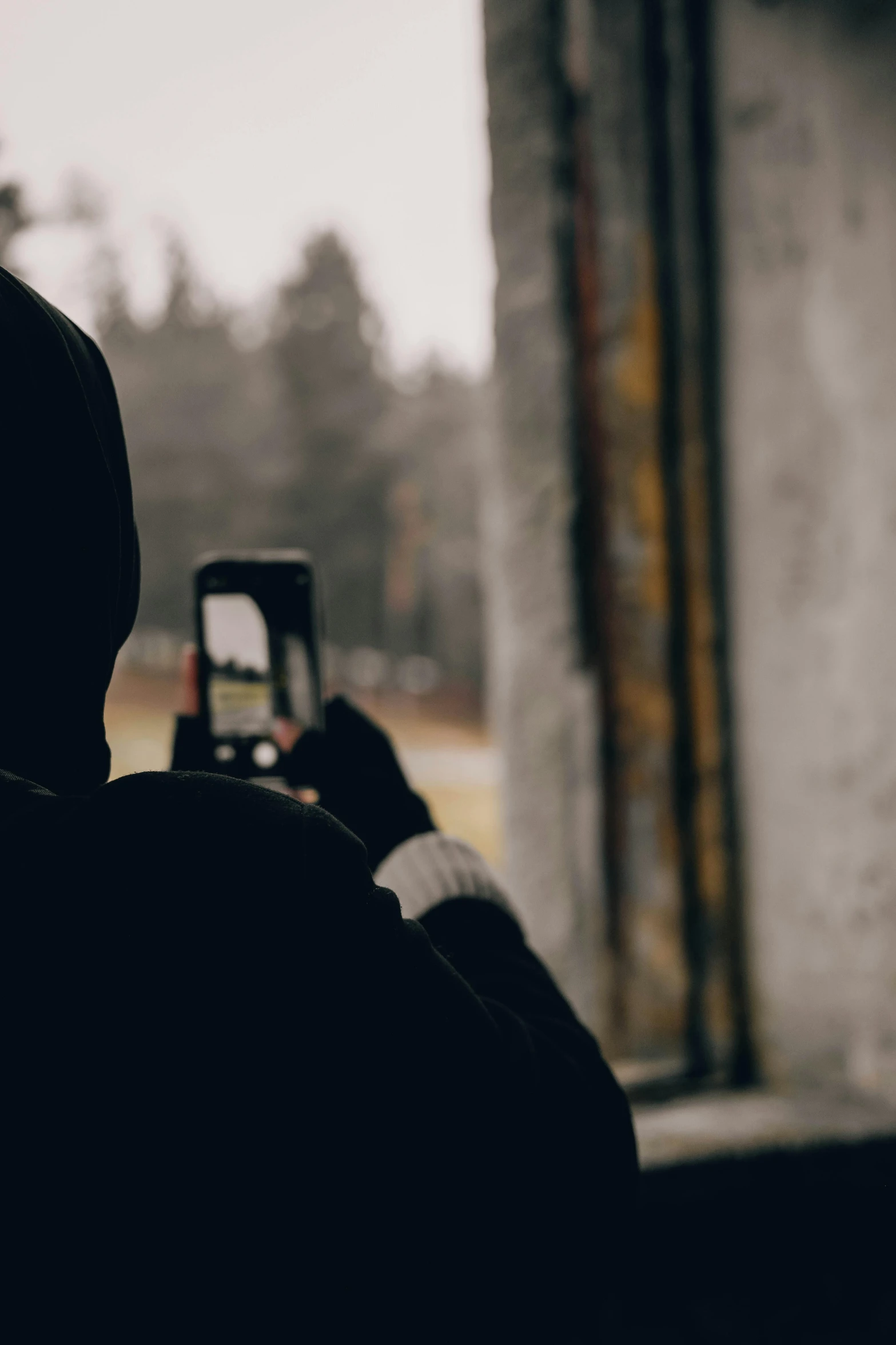 person in black jacket taking po with cell phone