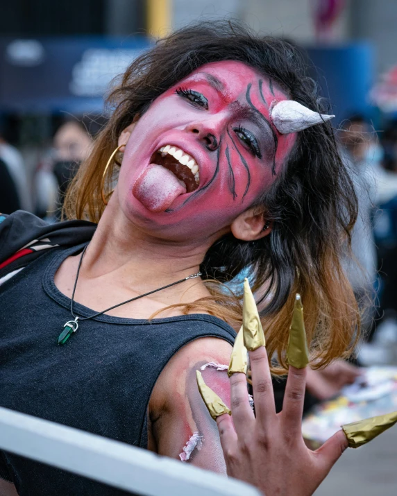 a woman with colorful makeup holds a knife and stares at the camera