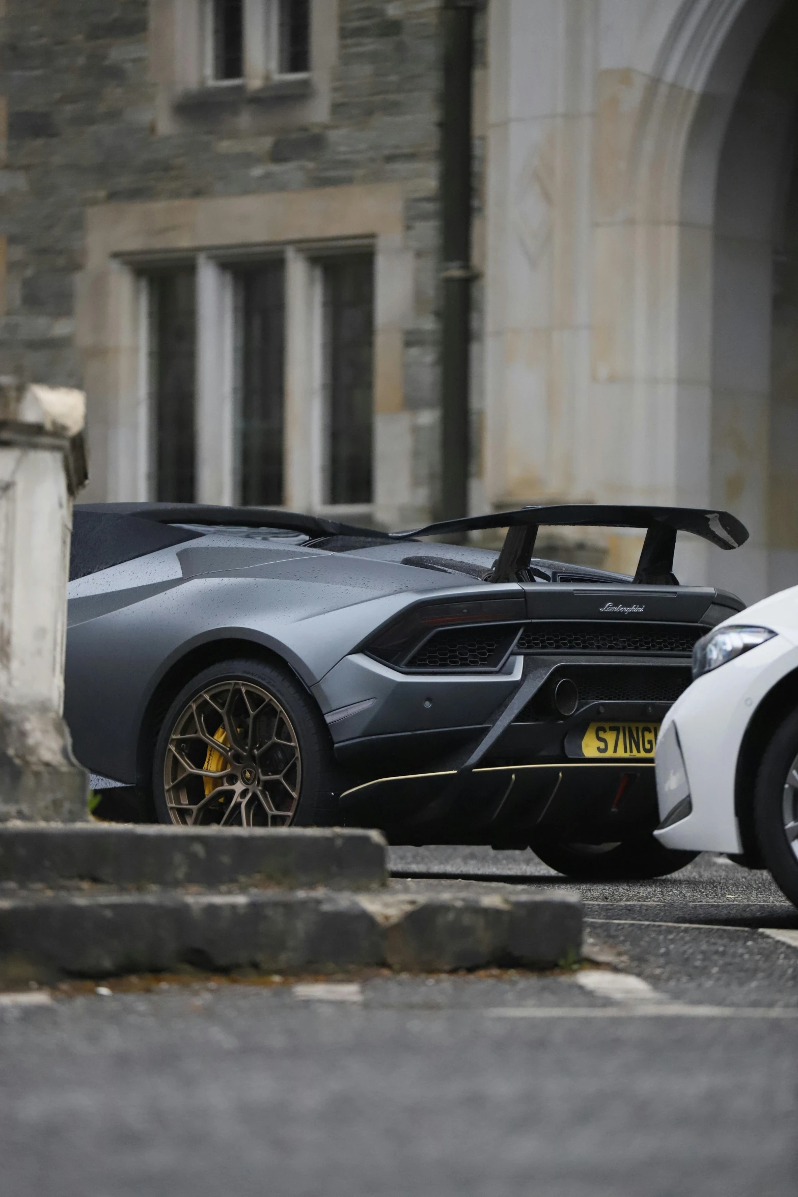 a large gray and black car parked near an old building