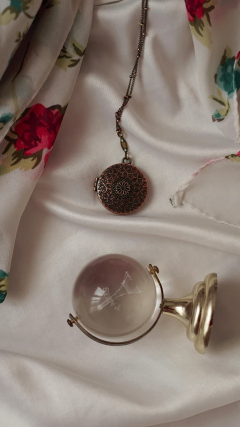 a white jewelry set with an old magnifier on a floral print cloth