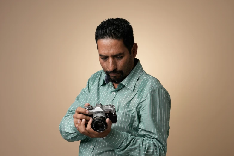 the man holding his camera while wearing a green shirt