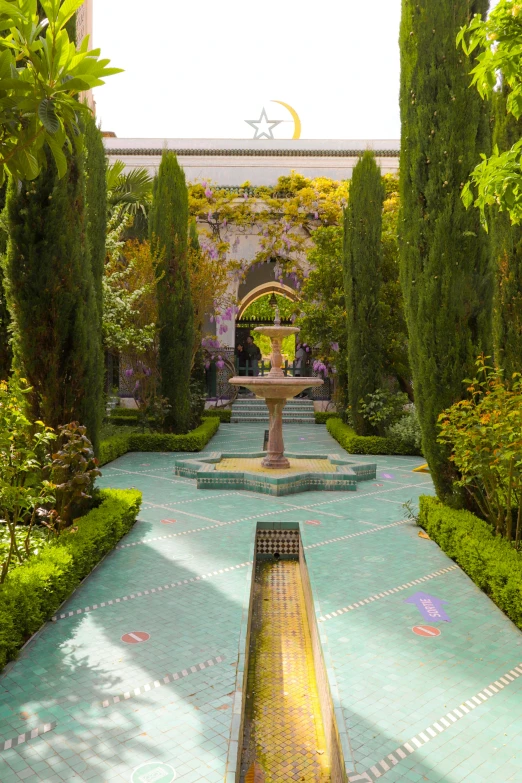 the fountain is surrounded by tall trees and bushes