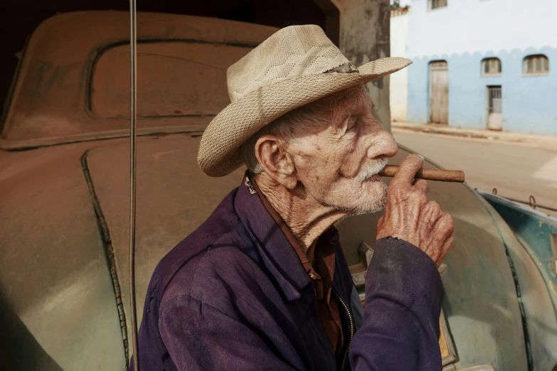 an old man with a hat smoking a cigarette