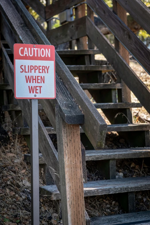 an outside stair way with a sign that reads caution slippery when wet
