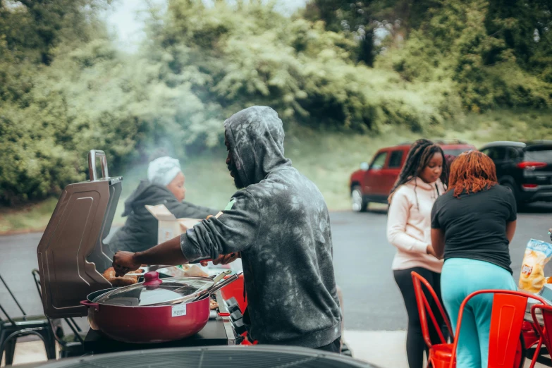 two women are eating outside while one man is sitting on a chair