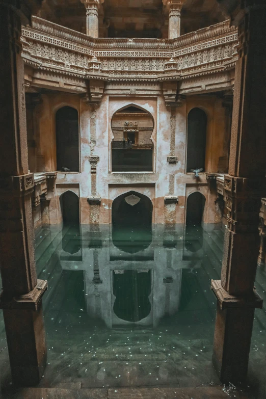 an old stone building has two arches and a pool in it