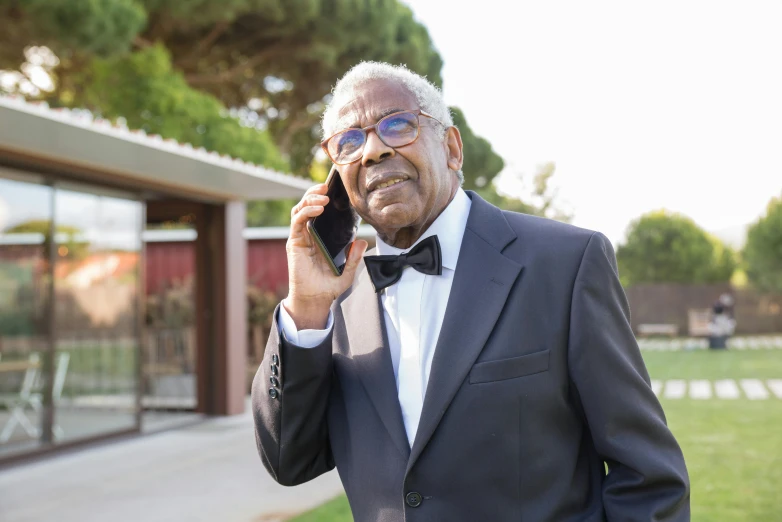 a man wearing a suit and bow tie talking on a cellphone
