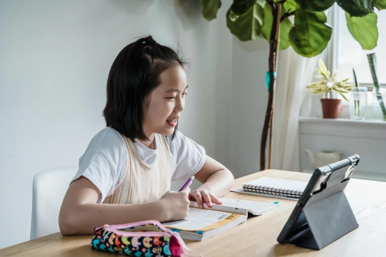 a little girl with an ipad at her desk