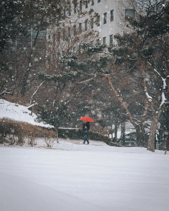 a man walking down a snow covered street holding an umbrella