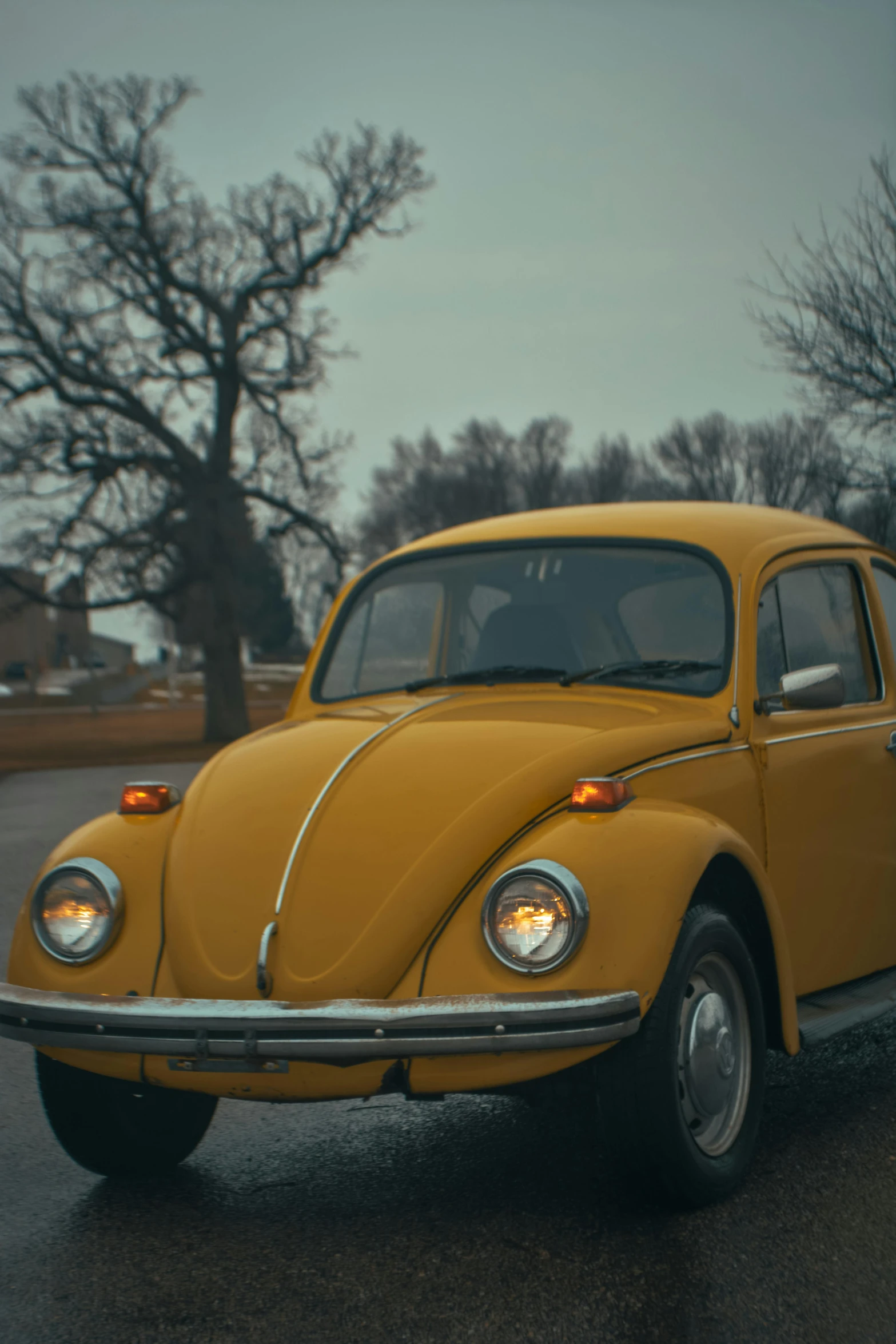 a yellow volkswagen beetle sits parked in a parking lot