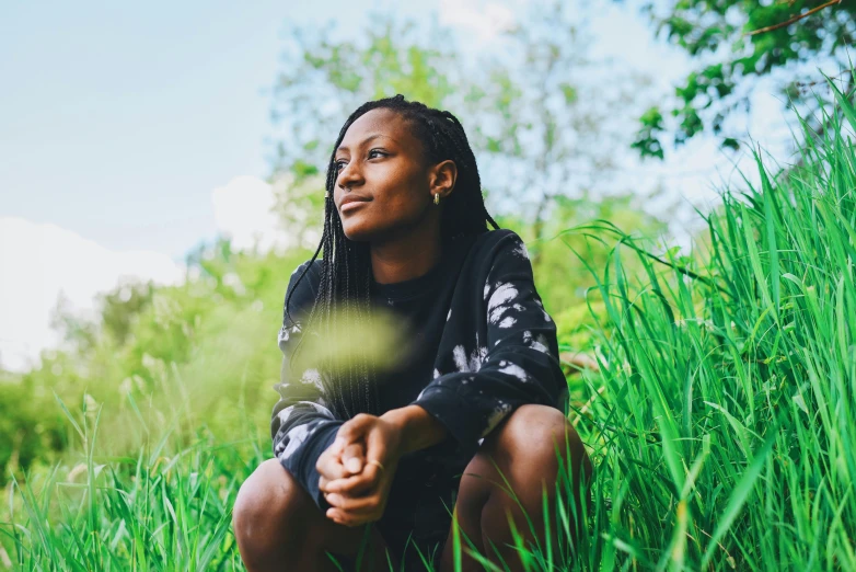 a woman in a black shirt is sitting on the grass