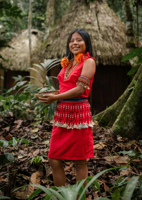 a woman in a red dress holding a small piece of fruit