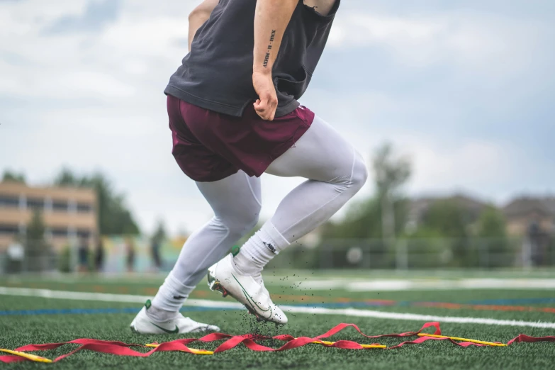 a man in grey shorts and maroon top kicking a frisbee