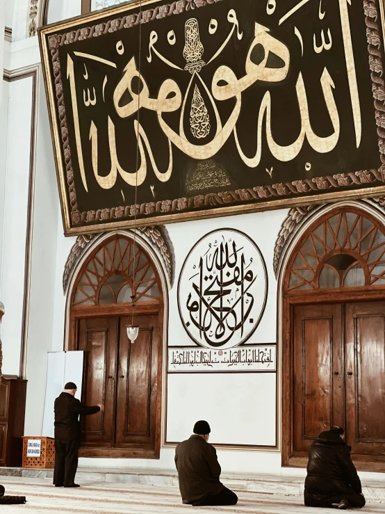 two men in muslim clothing pray beneath the names of the five priests