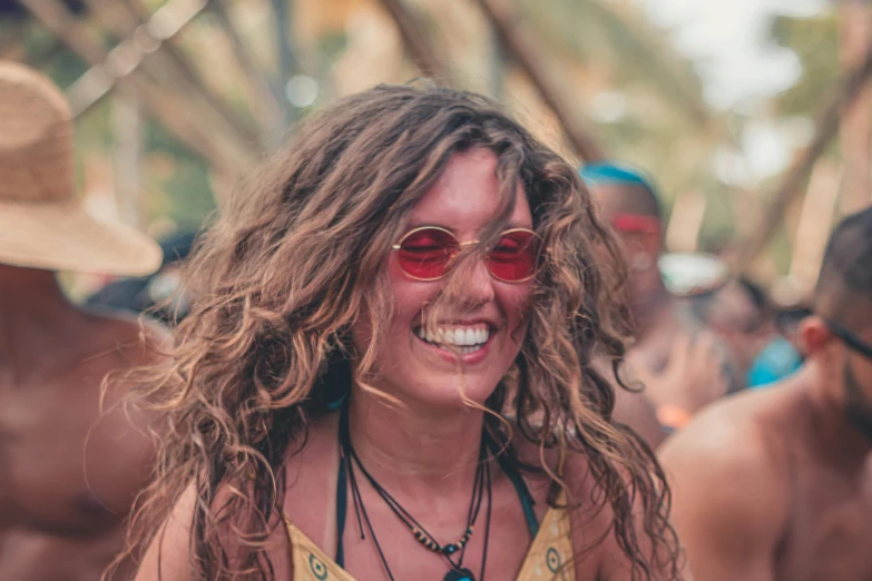 a woman in red sunglasses and a straw hat smiles