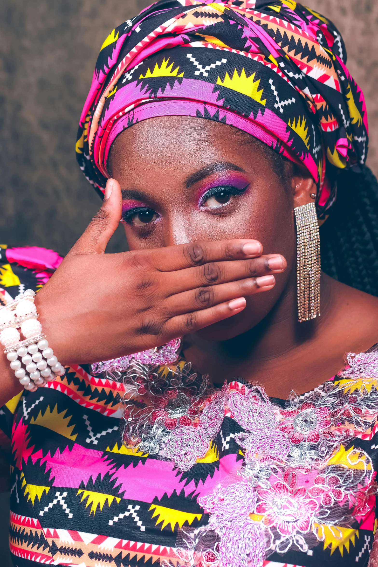 a woman dressed in a colorful top holds her hand to her face