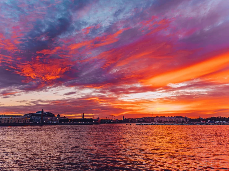 the sunset on the water with some pink clouds