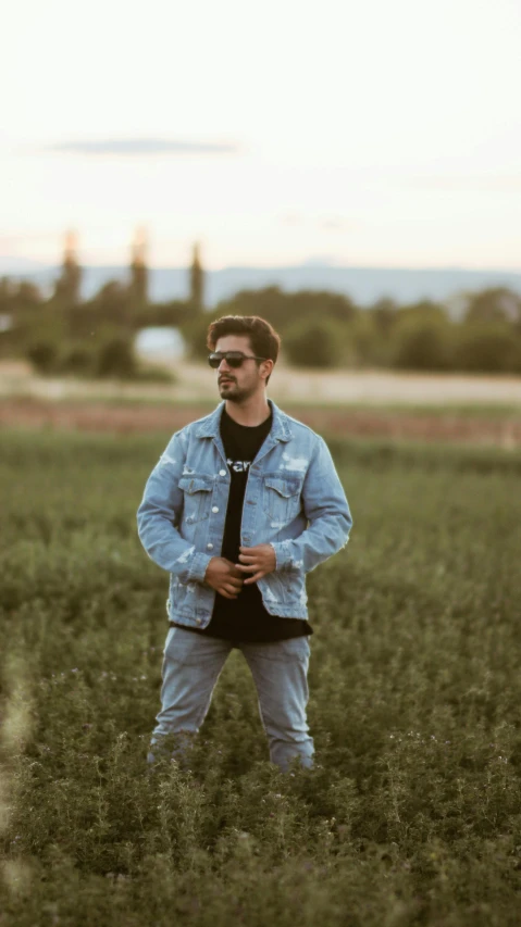 a man standing in tall grass wearing sunglasses