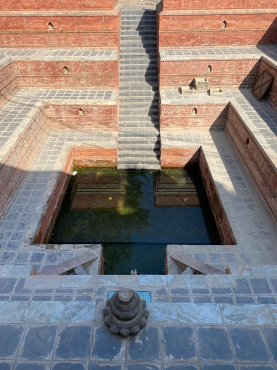 a stone building with bricks surrounding a pond