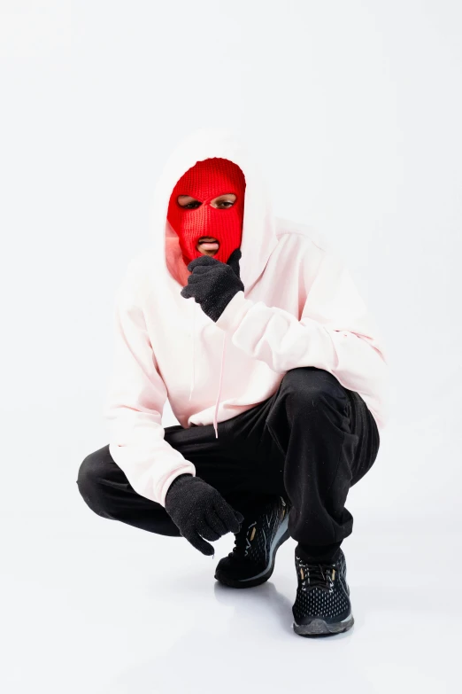 a person in a hoodie squatting down wearing a mask