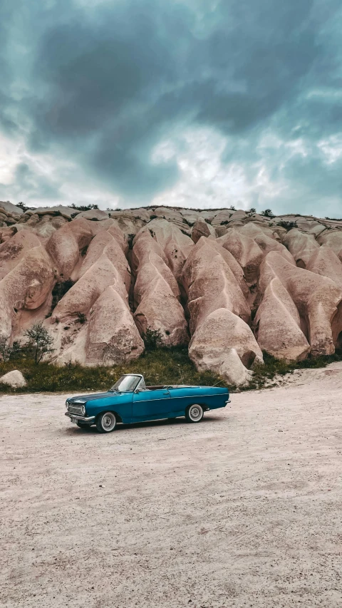 a vintage blue car in front of a rock formation