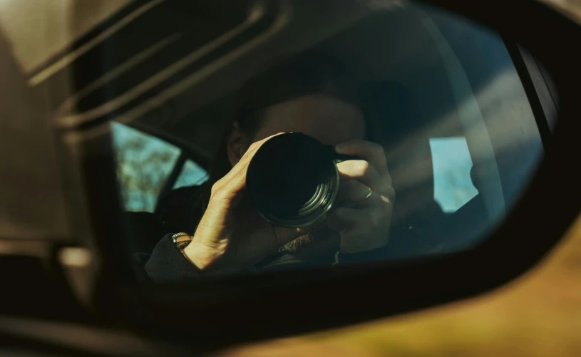 a man taking a picture in the side mirror of a car