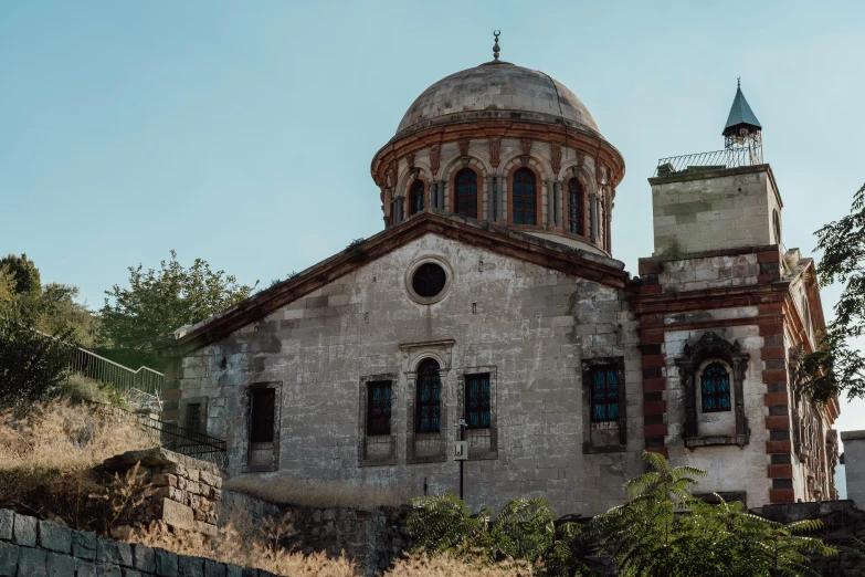 an old building with windows and a steeple on a hill