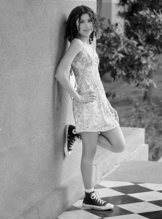 a beautiful young woman leaning on a building