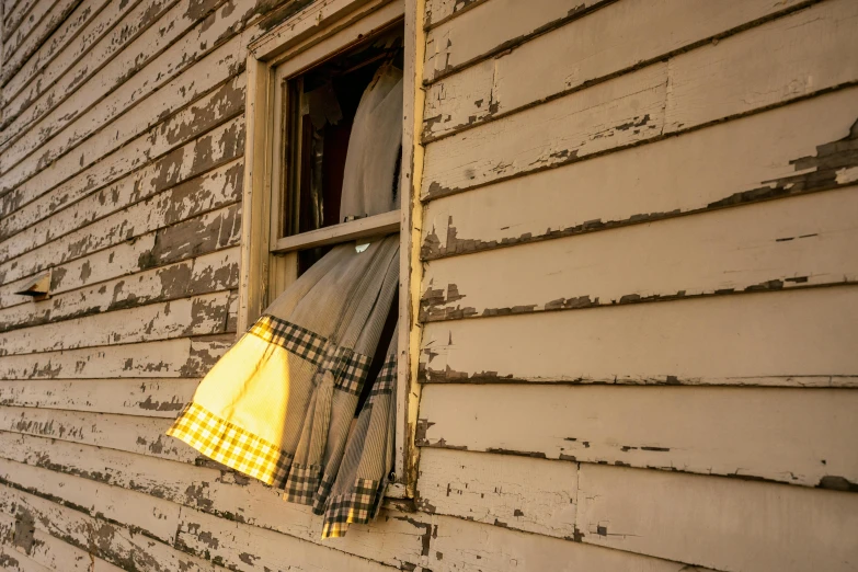 an old window with some pieces of cloth hanging from it