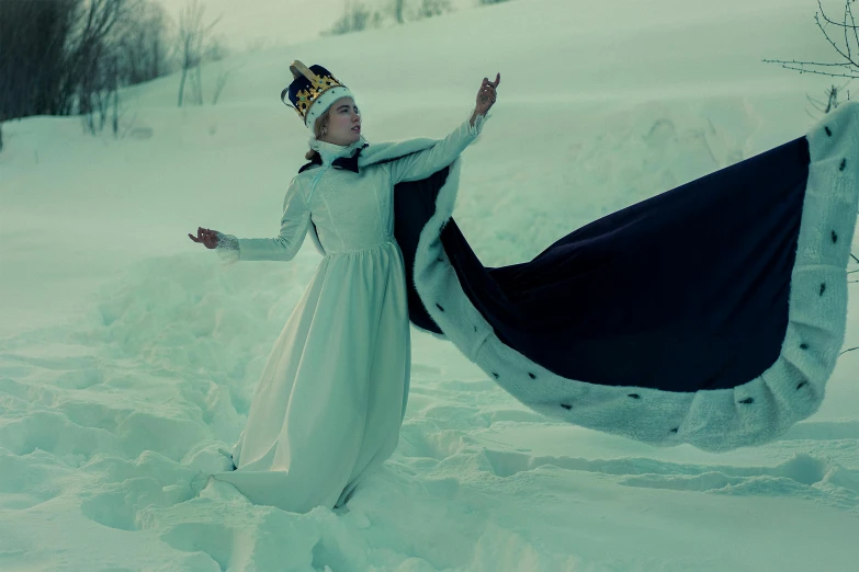 a woman wearing a long dress and hat in the snow