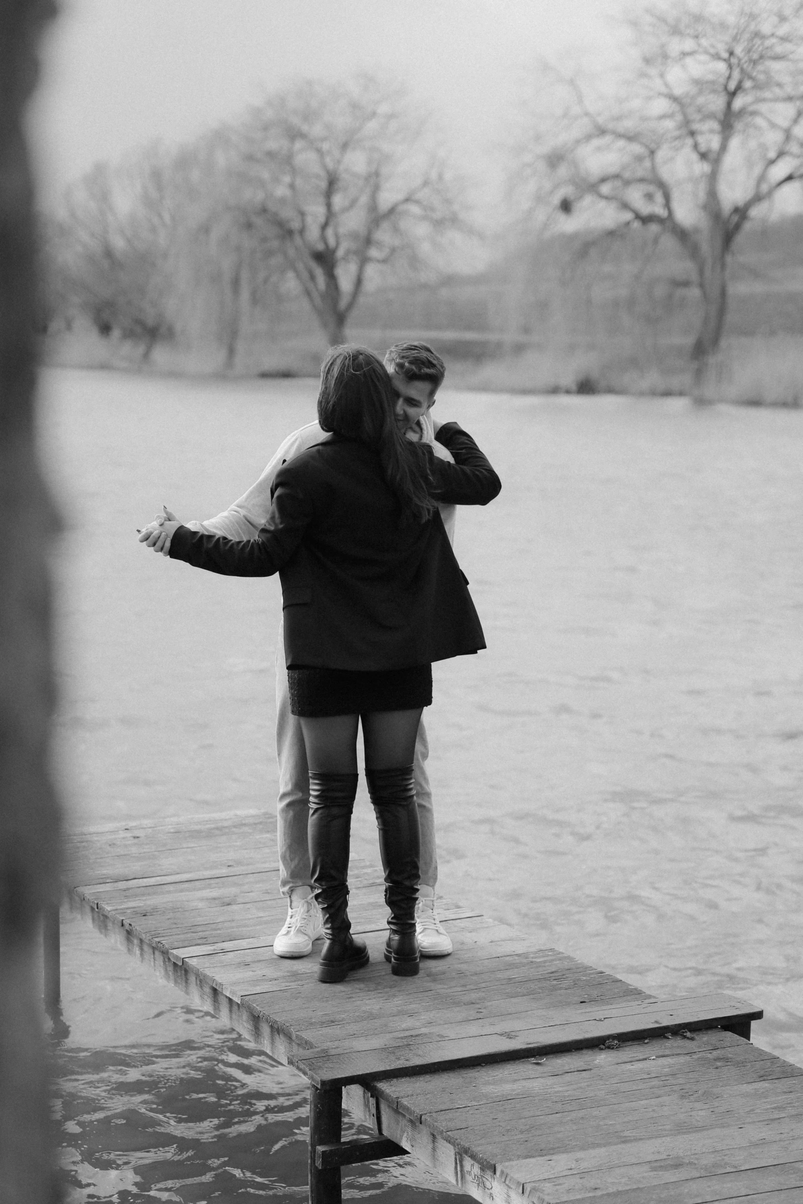 two people standing on a dock with water in the background