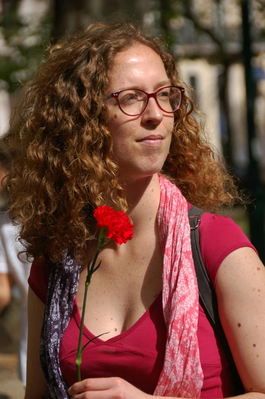 the woman is holding a red rose in her hand