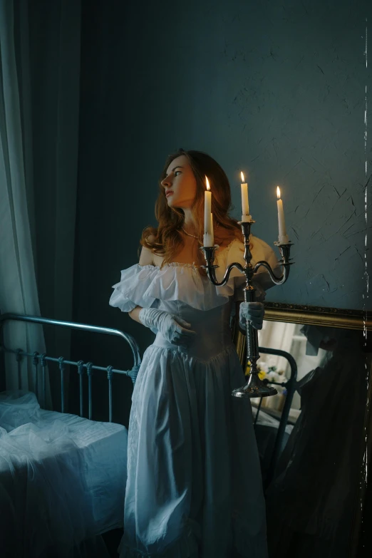 the woman stands next to a bed with candles on it