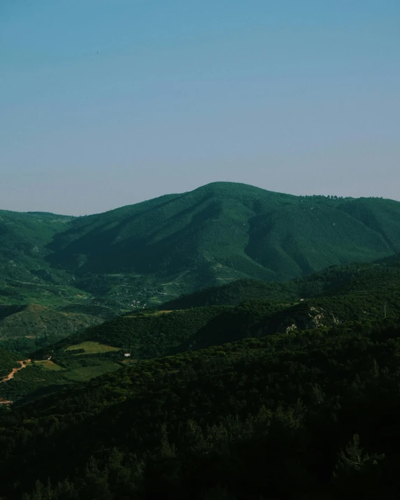 hills with grass growing on them and a hill in the background