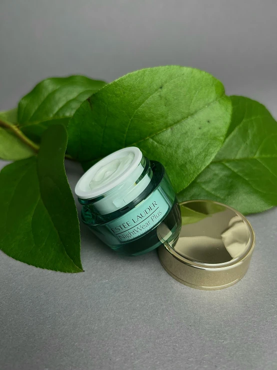 a green jar containing eye cream sitting on a counter