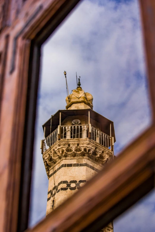 an ornate tower reflected in a mirror, against the blue sky