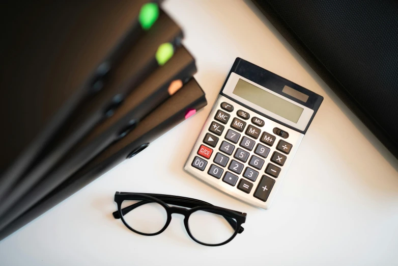 glasses and a calculator sitting on a table