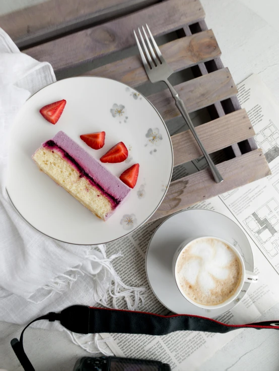 a white plate topped with cake next to a cup of coffee